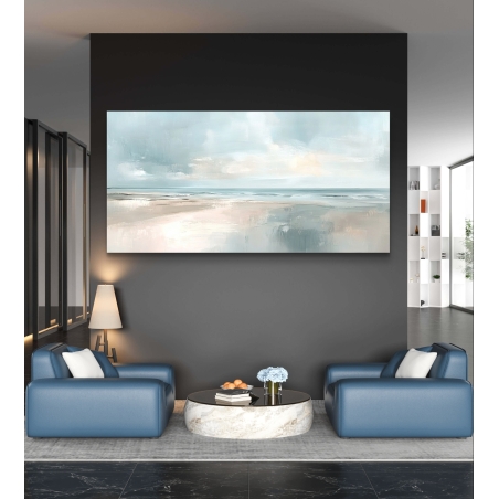 תמונת קנבס רחבה של נוף חוף ים רגוע בצבעים בהירים ותכלת, תלויה מעל ספה בגוון שמנת בסלון מודרני עם שולחן עגול משיש.