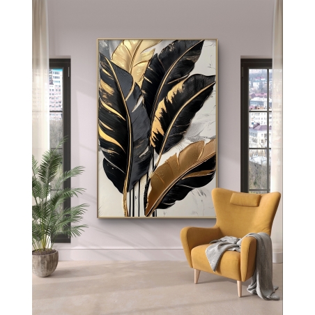 תמונת קנבס עם עלים בגווני שחור וזהב תלויה על קיר מודרני ליד כורסה בצבע חרדל.