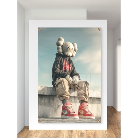 תמונת זכוכית של דמות KAWS יושבת על גג עירוני עם קפוצ'ון כהה ונעלי סניקרס אדומות – מתוך קולקציית NEXTGEN BY BAR של תכשיט לבית.