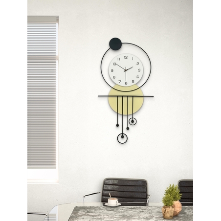 שעון קיר מעוצב בסגנון מודרני עם צורות גאומטריות, מסגרת עגולה, מטוטלות דקורטיביות וגימור אלגנטי בגווני שחור, לבן וזהב, תלוי על קיר בהיר.