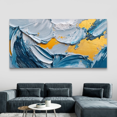 תמונת קנבס מופשטת עם מרקם גולמי בגווני כחול, תכלת וזהב תלויה מעל ספה אפורה בעיצוב מודרני.