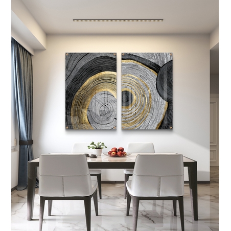 סט תמונות זכוכית זוג בעיצוב אבסטרקטי עם מעגלים קונצנטריים בגווני שחור, אפור ולבן עם נגיעות זהב מעל ספה מודרנית כחולה.