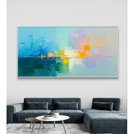 תמונת קנבס רחבה בגוונים של כחול, כתום, טורקיז וצהוב, תלויה מעל ספה אפורה בסלון בעיצוב מודרני.
