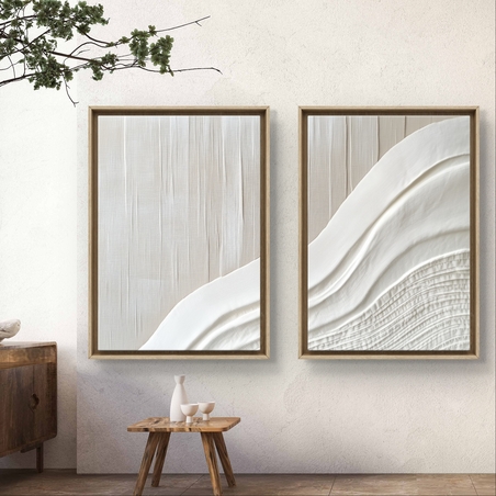 זוג תמונות קנבס בגווני שמנת עם הדפס טקסטורלי המדמה אריג חלק וגלי, בעיצוב מינימליסטי ורך, תלוי על קיר בסלון מודרני עם פריטים מעץ וטון טבעי.