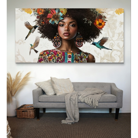תמונת קנבס גדולה של אישה אפריקאית עם שיער מתולתל עטור פרחים צבעוניים, עגילים גדולים וציפורי יונק דבש ברקע, תלויה מעל ספה ירוקה בסלון מודרני.