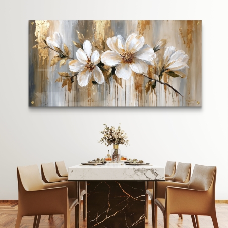 תמונת זכוכית לרוחב עם שלושה פרחים לבנים ונגיעות זהב תלויה מעל שולחן אוכל מודרני עם כיסאות לבנים.