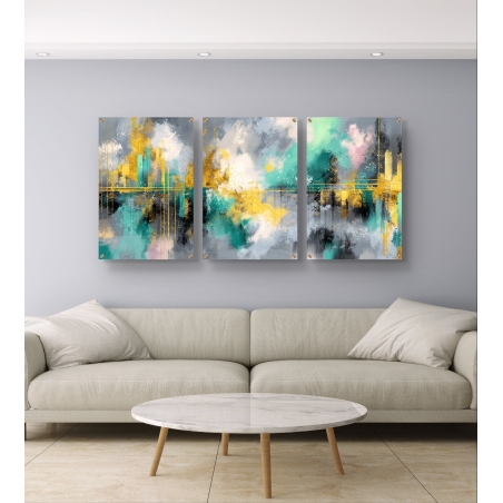 שלוש תמונות זכוכית בגווני טורקיז, זהב ואפור, עיצוב מופשט עם השתקפות עירונית על קיר סלון בגוון אפור, מקולקציית תכשיט לבית.