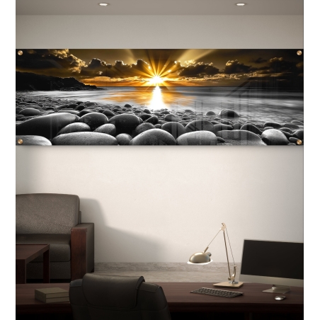 תמונת זכוכית פנורמית המציגה זריחה מרהיבה מעל חוף אבנים דרמטי. שילוב של צבעי זהב וניגוד שחור-לבן, בגימור יוקרתי שמוסיף עומק לכל עיצוב פנים.