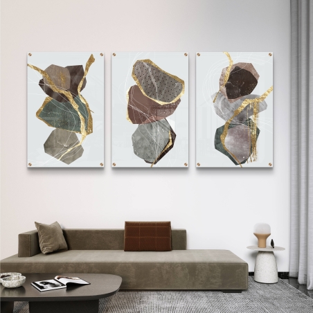 תמונה שלישיית זכוכית בסגנון מופשט עם אלמנטים גאומטריים בגווני חום, ירוק וזהב, על רקע בהיר עם קווים דינמיים, תלויה מעל ספה מודרנית כהה.