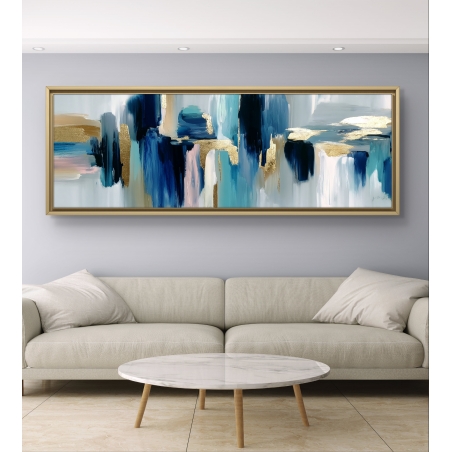 תמונה פנורמית מופשטת בגווני כחול, תכלת, ורוד וזהב, מודפסת על קנבס חלק, תלויה מעל ספה בסלון מודרני.