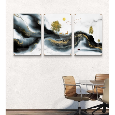 שלוש תמונות זכוכית עם נוף הרים בשחור ולבן, עצים מוזהבים ואיילים, תלויות מעל ספה מודרנית בגוונים ניטרליים.