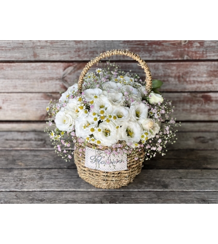 A white arrangement with pink gypsophila in a basket