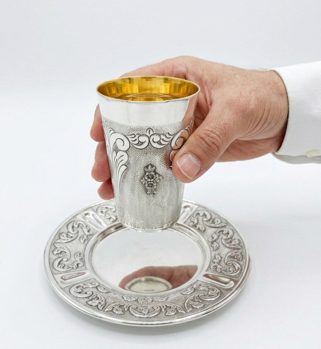 A hand holding a quality Kiddush set, decorated by hand in pure 925 silver