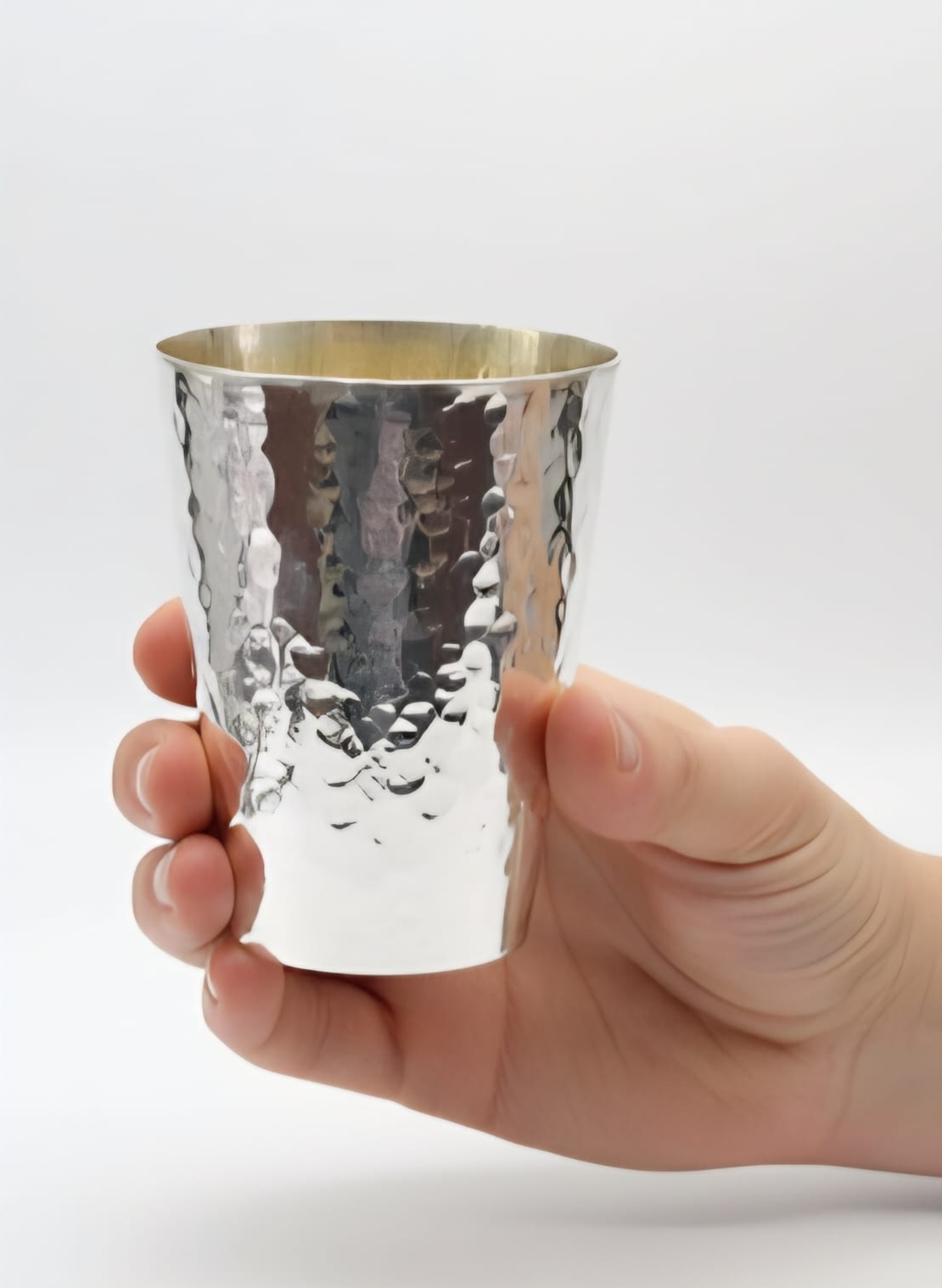 Hand holding a handmade Kiddush cup, hammered from pure 925 silver, made in Israel