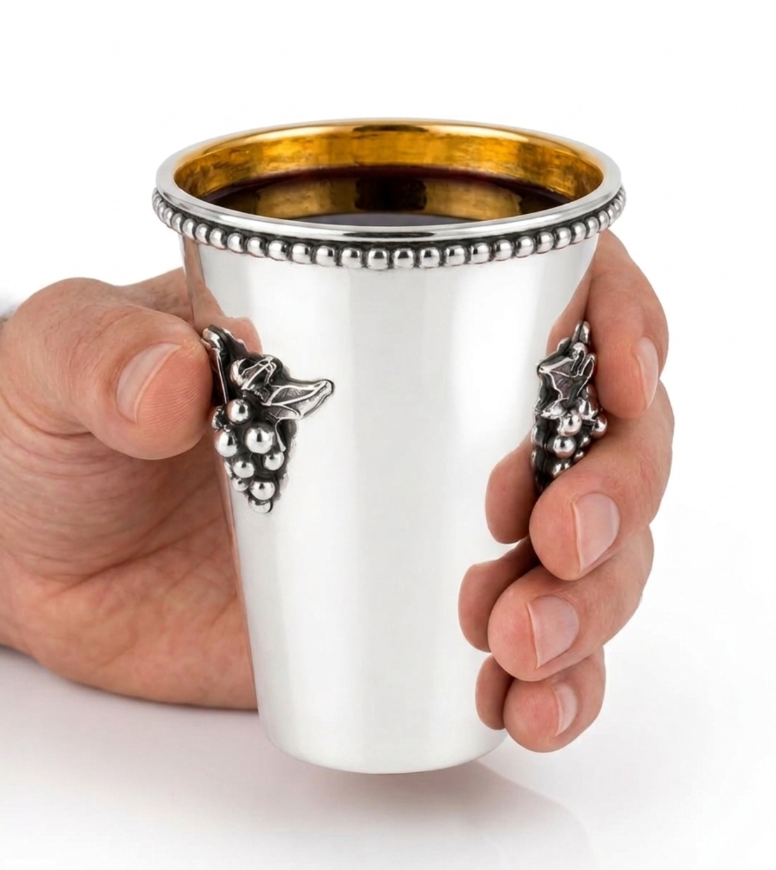 Hand holding a pure silver Kiddush cup, handmade with grape decoration