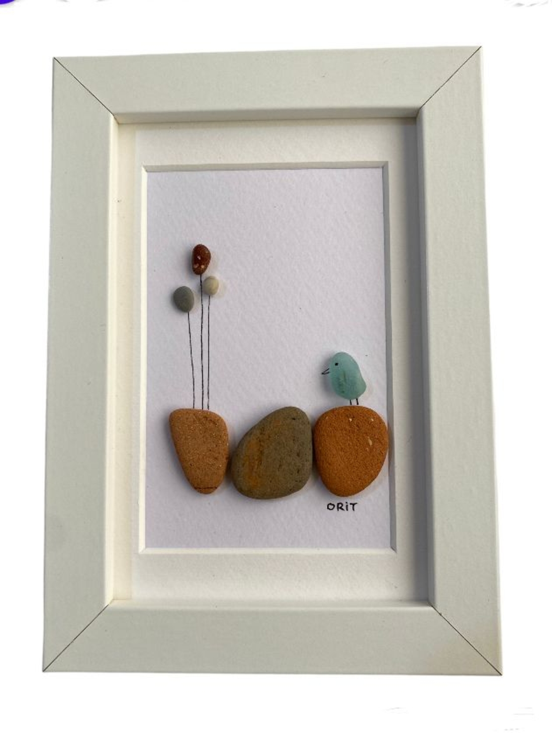 בלונים וציפור שעומדת על הסלעים עשויים מזכוכיות אבנים וחרסים שנאספו בחופי הארץ ובעולם