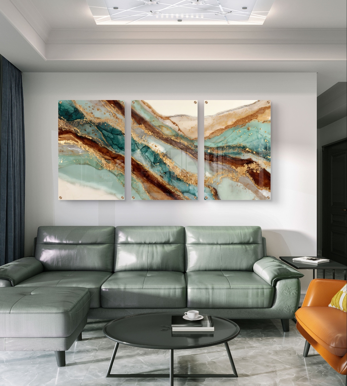 תמונת זכוכית מחולקת לשלושה חלקים בעיצוב שיש אבסטרקטי בגווני טורקיז, חום וזהב תלויה מעל שולחן אוכל מודרני.