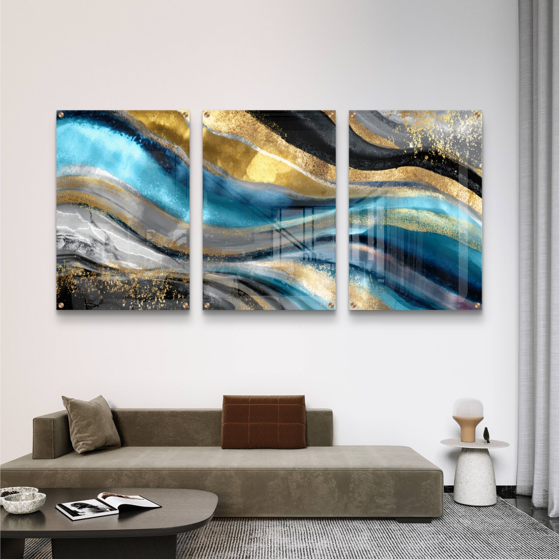 תמונת זכוכית מחולקת לשלושה חלקים בגווני טורקיז, שחור וזהב בעיצוב אבסטרקטי מודרני תלויה מעל שולחן אוכל לבן.