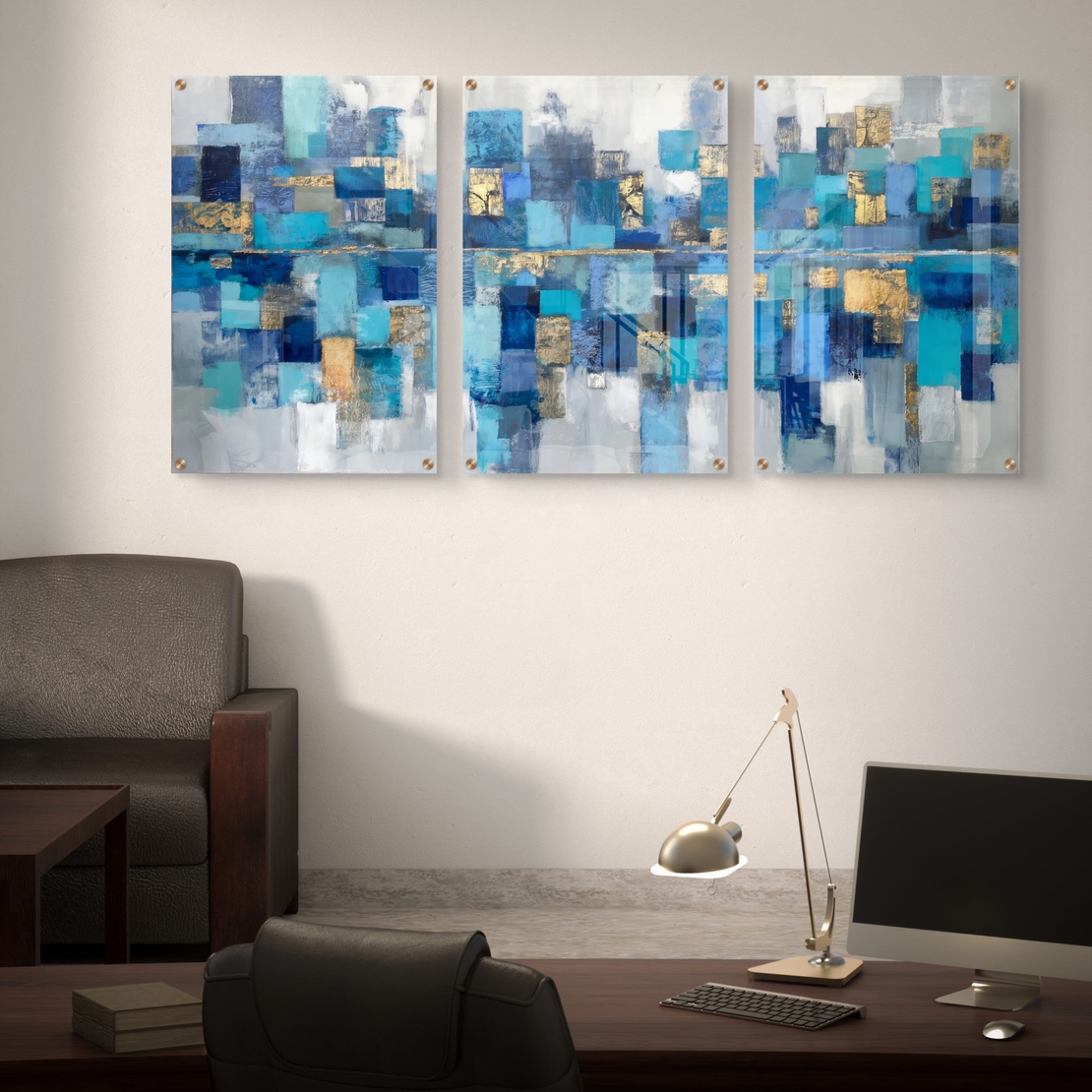 תמונת זכוכית מחולקת לשלושה חלקים בעיצוב אבסטרקטי בגווני כחול, טורקיז וזהב תלויה מעל שולחן אוכל מודרני.