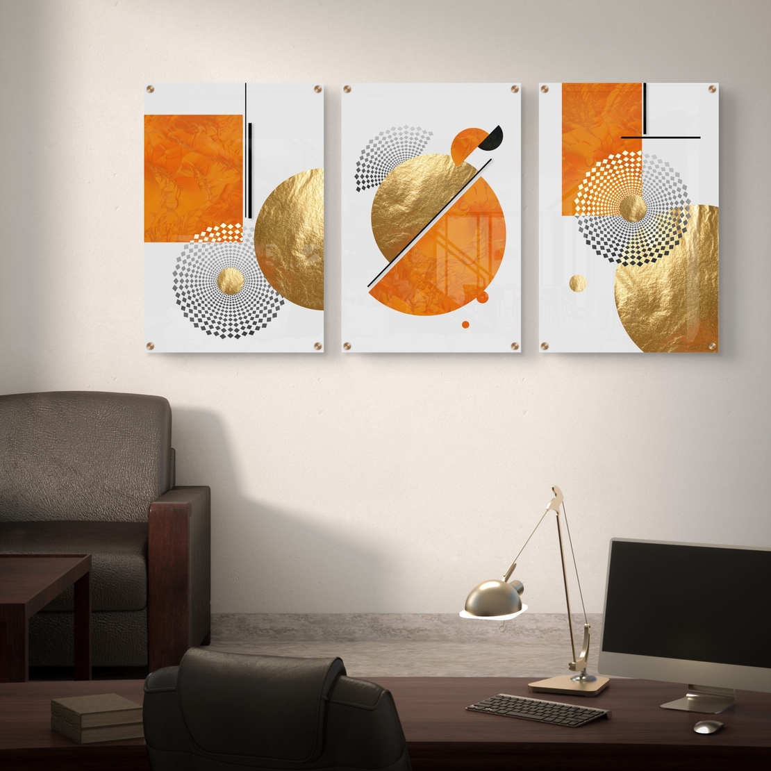 תמונת זכוכית מחולקת לשלושה חלקים בעיצוב גיאומטרי בגווני כתום וזהב תלויה מעל ספה מודרנית בסלון.