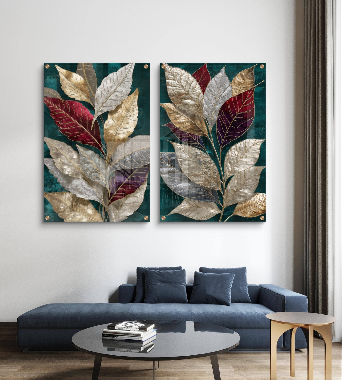 סט תמונות זכוכית זוג עם עלים גדולים בגווני זהב, בורדו ושמנת על רקע ירוק אמרלד תלוי מעל ספה כחולה בסלון מודרני.
