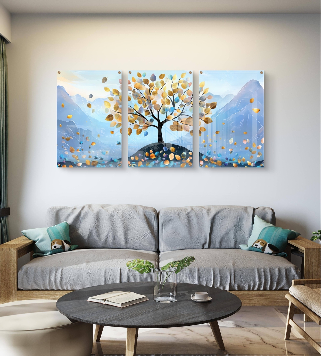 תמונת זכוכית שלישייה עם עץ ועלים בגווני תכלת וזהב על רקע הרים בעיצוב רגוע
